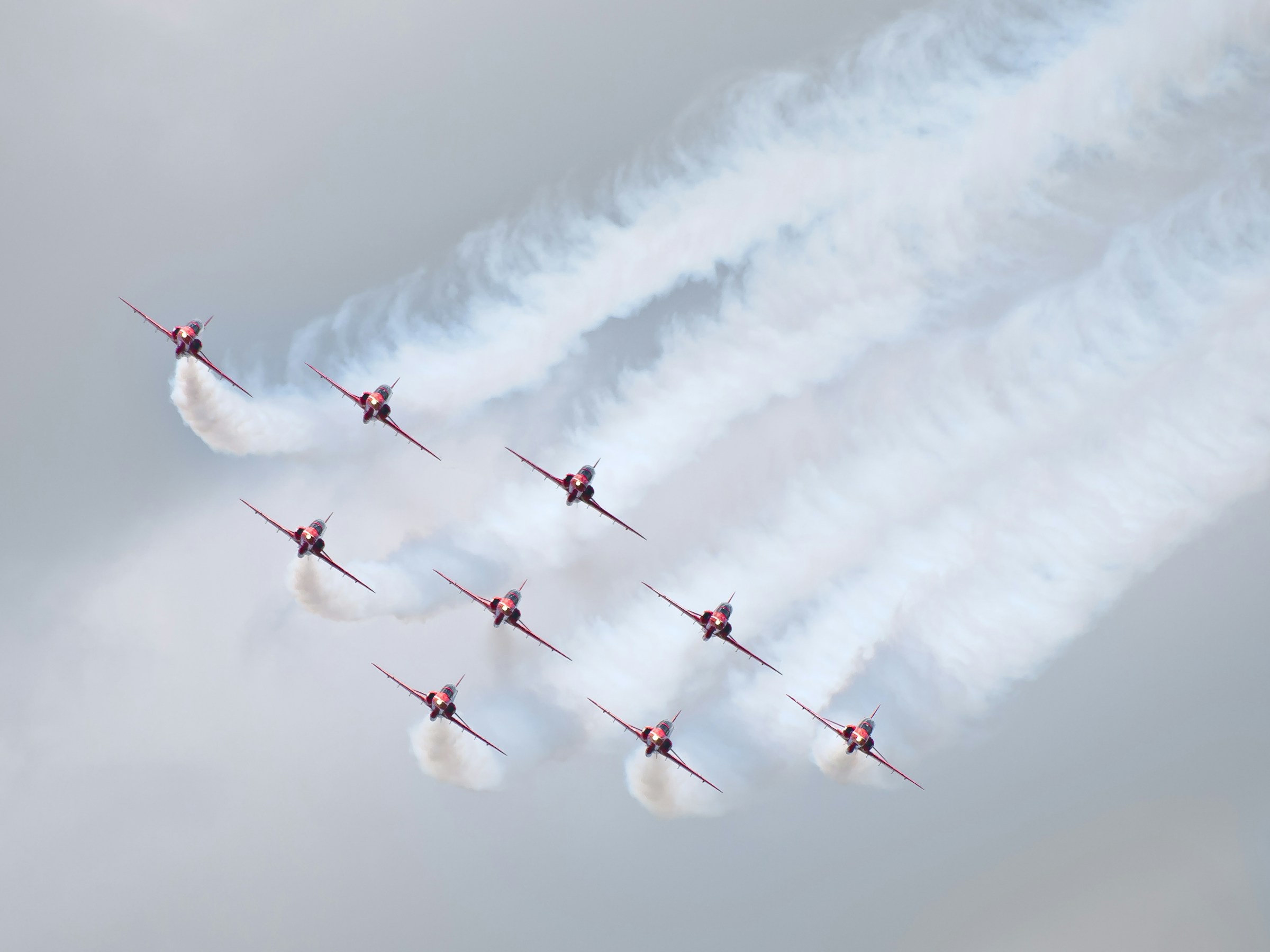 Red Arrows banking together, leaving long white smoke trails